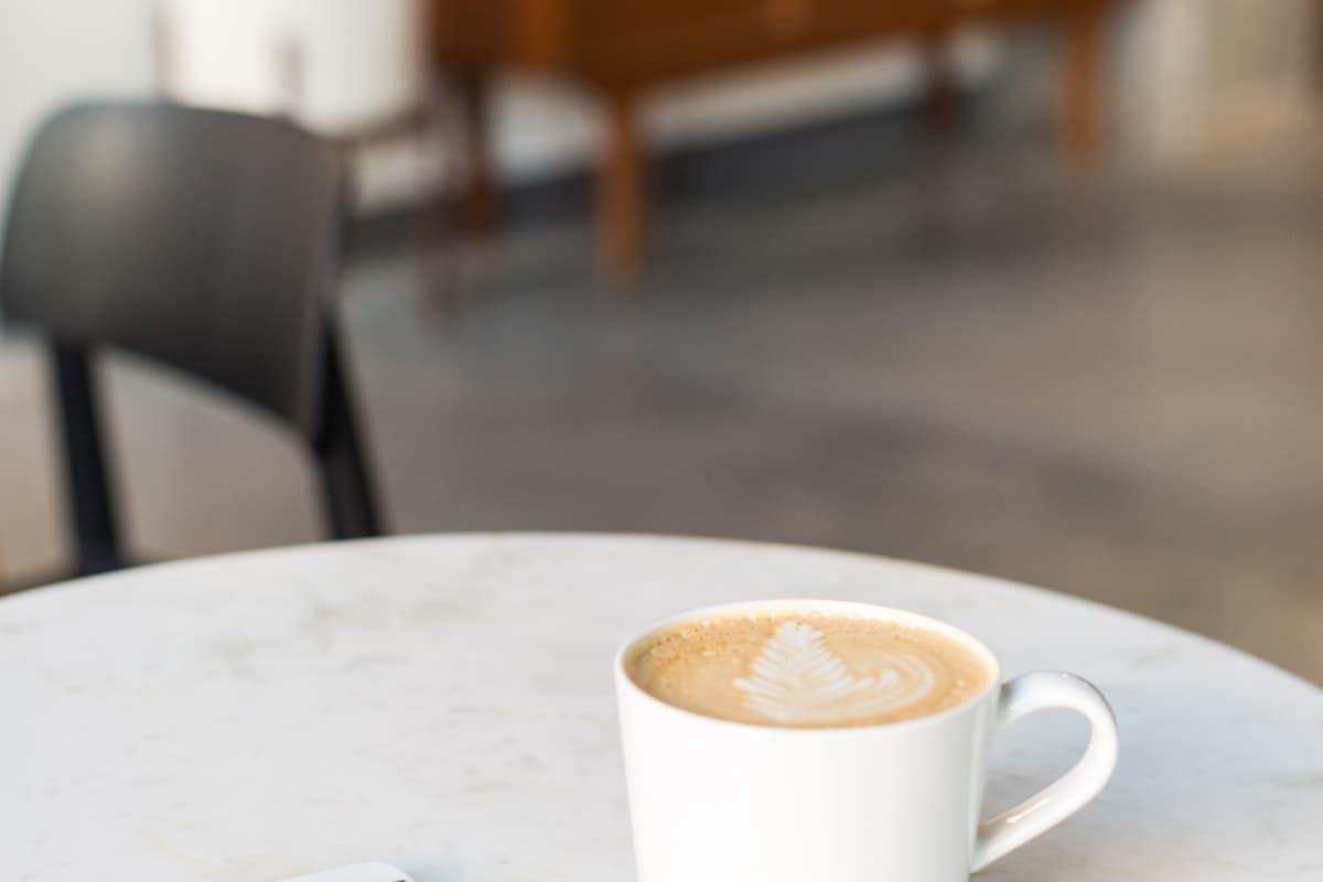 A coffee cup beside a phone on a cafe table